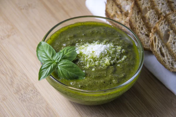 Pesto verde con foglie di basilico fresco in piccola ciotola di vetro su fondo di legno — Foto Stock