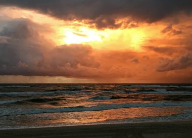 Yanan bulutlar. Baltık Denizi üzerinde dramatik bir gökyüzü. Litvanya, Nida yakınlarındaki Curonian Tükürüğünde Günbatımı.