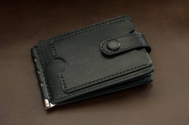 Kahverengi arka planda siyah deriden yapılmış cüzdan.