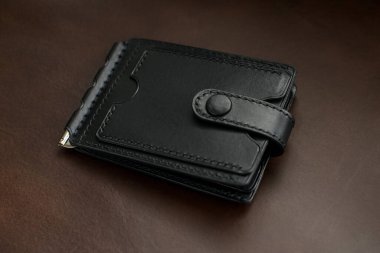 Kahverengi arka planda siyah deriden yapılmış cüzdan.