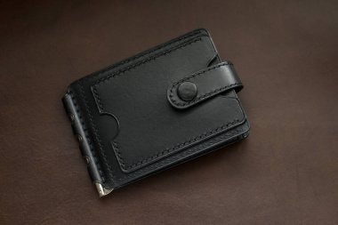 Kahverengi arka planda siyah deriden yapılmış cüzdan.