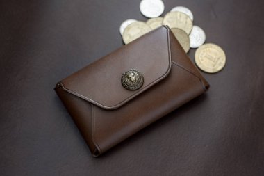 Kahverengi arka planda siyah deriden yapılmış cüzdan.