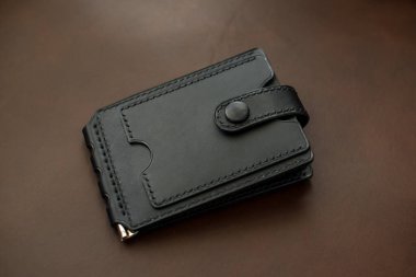 Kahverengi arka planda siyah deriden yapılmış cüzdan.