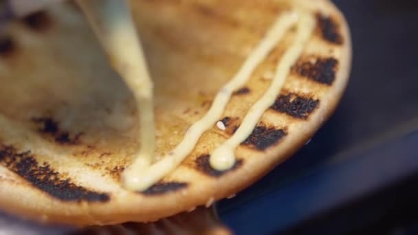 Cozinheiro espalha um molho branco sobre um pão — Vídeo de Stock