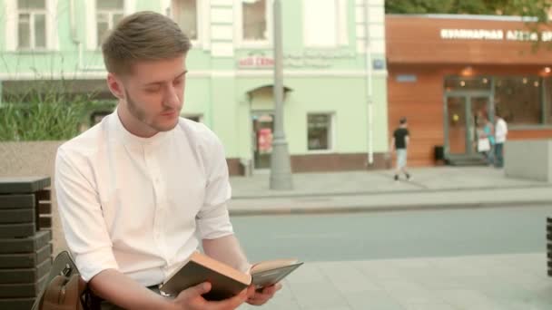 Молодой человек читает книги на открытом воздухе — стоковое видео