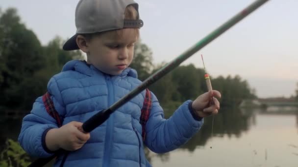 Aktiv liten pojke som håller spinning stång med flöte tillbringa tid utomhus vid naturliga flod damm — Stockvideo