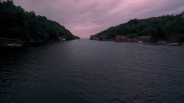 Gün batımında sakin su yüzeyinde uçan hava görüntüleri dağlardaki köy evleriyle çevrili.