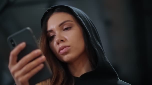 Closeup of a Modern teenager girl in a hood using a smart phone inside a gym — Stock video