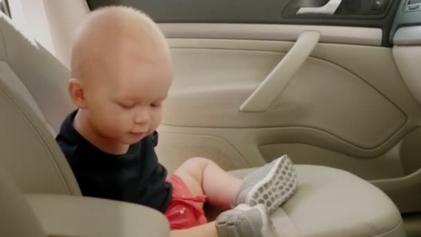 Menino em um assento de motorista sentado pacientemente em um carro olhando curioso dentro — Vídeo de Stock