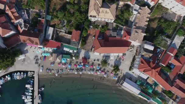 Tiro estático aéreo turístico pessoas relaxantes andando na praia do mar em telhados da aldeia da cidade de casas — Vídeo de Stock