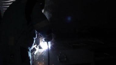 Koruyucu maskeli erkek demirci metal demir kaynak makinesiyle çalışıyor.