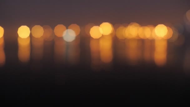 Seascape closeup νερό ηρεμία ομαλή επιφάνεια κίτρινο αναβοσβήνει φως bokeh παραλία παραλία στη θάλασσα τη νύχτα — Αρχείο Βίντεο