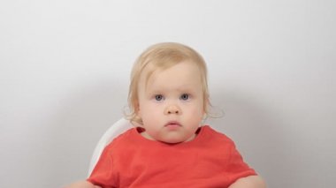 Beslenme koltuğunda oturan kırmızı pijama giyen sevimli küçük bir çocuğun orta boy yakın portresi.