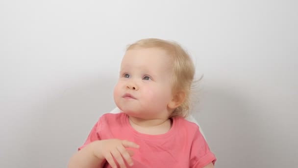 Niedliches kleines Kind zeigt gestikulierend die Hände, sitzt im Fütterungsstuhl und lächelt entspannt isoliert auf weißem Grund — Stockvideo