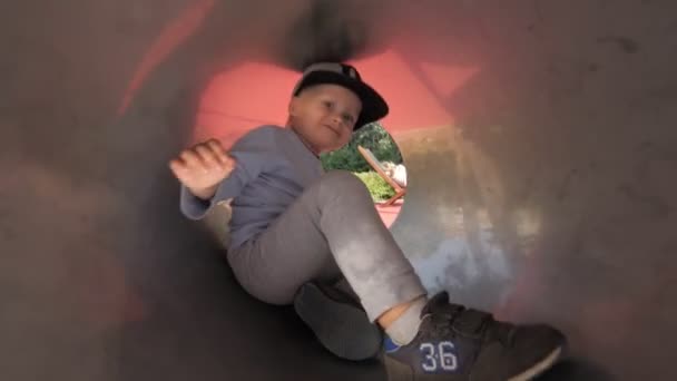 Engraçado menino jogando no slide atração no parque infantil rindo se divertindo — Vídeo de Stock