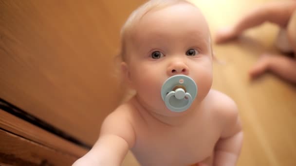 Cara de primer plano de niño divertido con chupete en la boca usando pañal jugando en casa bebé niño — Vídeos de Stock