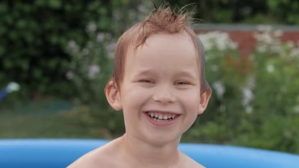 Closeup face of wet laughing funny little boy floating at inflatable rubber swimming pool — Stockvideo
