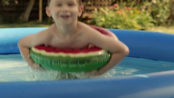 Menino alegre que sorri saltando na bóia de segurança da melancia na piscina de borracha inflável — Vídeo de Stock