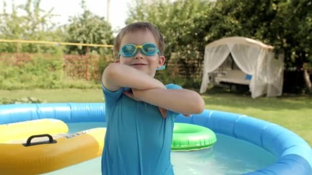 Portré vicces kisfiú pózol keresztbe tett kézzel közelében felfújható gumi medence — Stock videók
