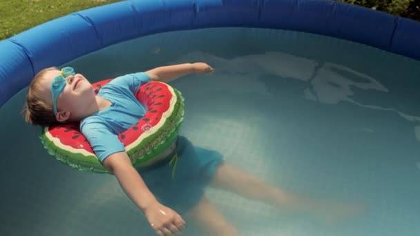 Bebê agradável sorrindo relaxante na bóia de segurança na piscina de borracha inflável — Vídeo de Stock