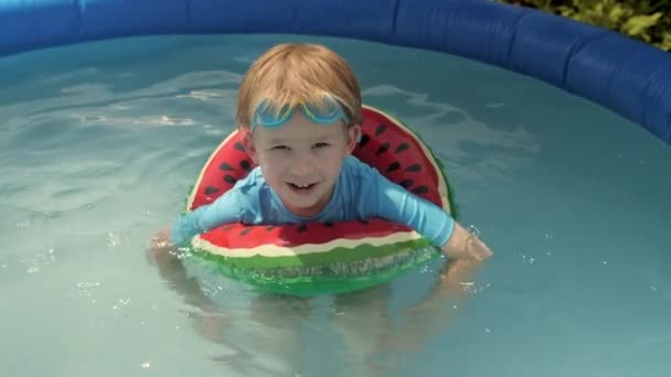 Roztomilý chlapeček plovoucí v vodní meloun bezpečnostní bóje tráví čas na nafukovací gumový bazén — Stock video