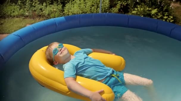 Grappige baby jongen zonnebaden op veiligheidsboei bij opblaasbaar rubber zwembad ontspannen — Stockvideo