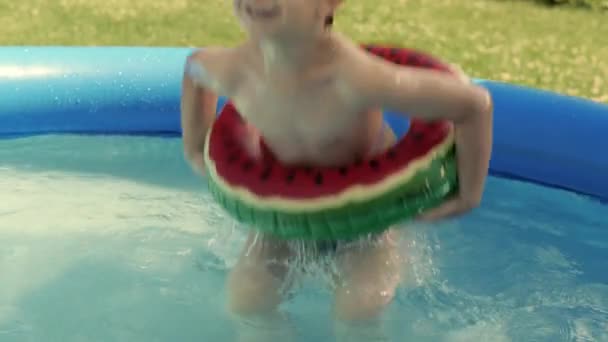 Liebenswerter kleiner Junge mit Sicherheitsboje springt an aufblasbarem Gummischwimmbecken — Stockvideo