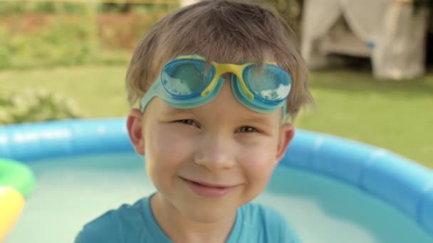 Adorabile ragazzo europeo che indossa occhiali di plastica protettivi sorridenti in posa nel cortile — Video Stock