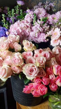 Çiçekçi dükkanındaki çeşitli taze çiçeklerin yakın plan görüntüsü, rengarenk çiçeklerle çevrili pastel pembe güller, ortancalar, papatyalar ve laleler