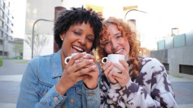 İki neşeli kadın birlikte kahvenin tadını çıkarıyorlar, keyifli sohbetler ve kahkahalar atıyorlar, sıcak içecekler ve iyi hisler eşliğinde arkadaşlar arasında paylaşılan neşeli anların özünü yakalıyorlar.