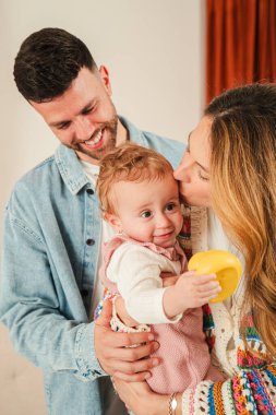 Sevimli ebeveynler, sevimli bebekleriyle değerli anların tadını çıkarıyorlar. Sevgi dolu öpücükler ve kucaklaşmalar paylaşıyorlar. Bu sevgi dolu aile toplantılarında ebeveynliğin özünü yansıtıyor.