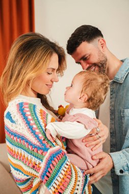 Sevgi dolu, samimi bir aile ortamında sevgi ve şefkat dolu sevimli bebeklerini kucaklayan ebeveynler arasındaki neşeli bağı gözler önüne seren yürek ısıtan bir an..