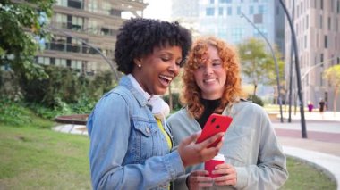 İki neşeli arkadaş, çeşitli mobil uygulamaları keşfetmek ve neşeli bir atmosferde kahkaha ve iletişimi paylaşmak için bir akıllı telefonla hoş bir şekilde meşgul oluyorlar..
