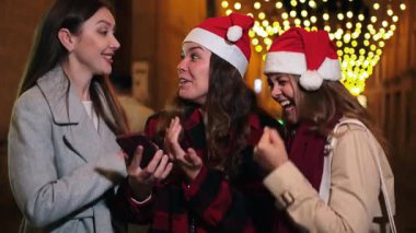 Bir grup heyecanlı kız tatil sezonunda neşeli tepkiler ve kahkahalar paylaşıyorlar birbirlerine sürpriz hediyeler veriyorlar ve arkadaşlıklarını heyecan ve mutlulukla kutluyorlar..