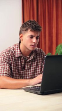 Genç bir adam dizüstü bilgisayarda çalışırken hayal kırıklığı yaşar, kendisini rahatsız eden bir sorunu düşünürken stres ve kafa karışıklığı belirtileri gösterir. Derin düşüncelere dalmış.