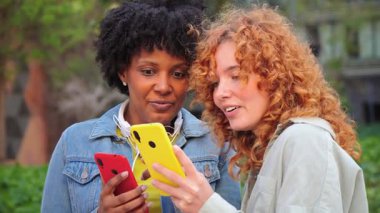 İki neşeli kız akıllı telefonlarını keyifle paylaşıyor, uygulamalar ve medya ile eğlenceli bir aktiviteye girişiyor, arkadaşlıklarını ve modern bağlantılarını keyifli bir zevk anında sergiliyorlar..