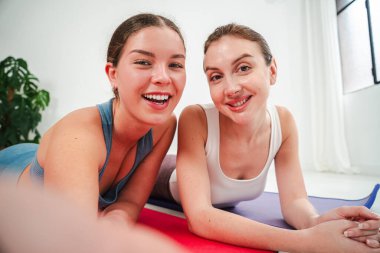 Neşeli bir yogaya katılan iki kadın birlikte neşeli bir selfie çekerken, dostluklarını ve spora bağlılıklarını gösteriyorlar, hepsi sağlık ve refahı desteklerken