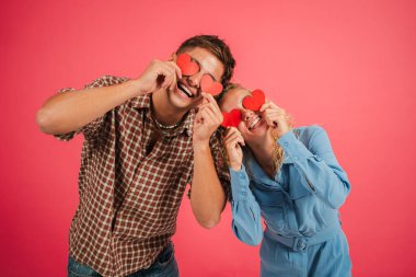 Mutlu çift neşeli bir şekilde kırmızı kalp şekillerini tutarken, birbirlerine olan sevgilerini ve sevgilerini gösteriyorlar..