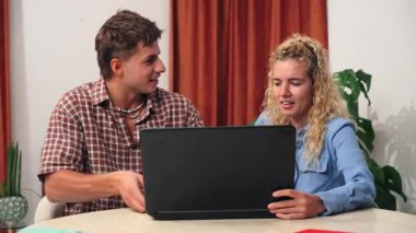 Yoğun bir sohbete katılan bir çift, dizüstü bilgisayar kullanırken, görevleri sırasında hayal kırıklığı ve anlaşmazlığın duygusal ifadelerini sergiliyor, karmaşık ilişkilerini yansıtıyor.