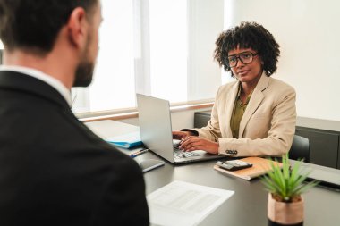 Yetenekli bir iş kadını resmi giyinmiş kendine güvenen bir adamla iş görüşmesi yapıyor. Bir masada önemli meseleleri tartışıyorlar. Bilgisayarı ve evrakları verimli bir şekilde kullanıyorlar..