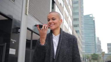 Kendine güvenen bir kadın akıllı telefonunu kullanırken hareketli bir şehirde profesyonelliğini ve dinamik iletişim becerilerini sergiliyor..