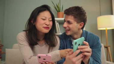 Birbirlerine eşlik eden mutlu çift, akıllı telefonlarıyla etkileşime geçerek, neşe ve bağlarla dolu rahat bir mekanda kahkahalar ve keyifli anlar paylaşıyorlar..