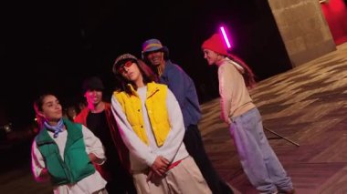 Hip hop hareketleri ve ritmik koreografi yoluyla müzik için yaratıcılıklarını ve tutkularını ifade ederek birlikte dinamik bir dans seansının keyfini çıkaran coşkulu bir grup genç arkadaş..