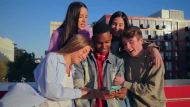 Neşeli gençlerin bir araya gelip birlikte zaman geçirmeleri akıllı telefon kullanmaları, gülücükler ve kahkahalar atmaları ve keyifli bir sosyal birlikteliktir.