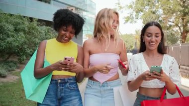 Bir grup neşeli kadın, canlı bir açık havada birlikte dolaşırken akıllı telefonlarıyla etkileşime giriyor. Teknoloji ve birbirleri ile olan bağlantılarını ve zevklerini gösteriyorlar..