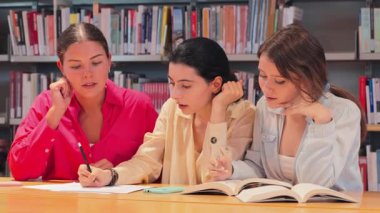 İşbirlikçi bir çalışma oturumuna katılan, fikirleri paylaşan, konuları tartışan ve öğrenme deneyimlerini ve akademik performanslarını geliştirmek için notlar alan üç öğrenciden oluşan odaklanmış bir grup..