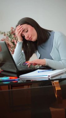 Hüsrana uğramış bir kadın dizüstü bilgisayarı üzerinde çalışırken gözle görülür stres belirtileri gösterir. Önündeki görevler onu şaşkına çevirmiş gibi görünüyor, uzak çalışmanın zorluklarını ve yerine getirmesi gereken baskıları gösteriyor.