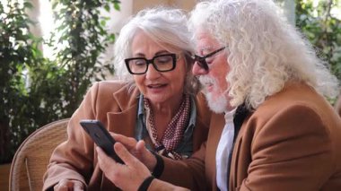 Zeki bir telefondan içeriği keşfederken keyifli, yaşlı bir çift kapalı bir ortamda teknoloji ile sevgi ve bağlantı sergiliyorlar..