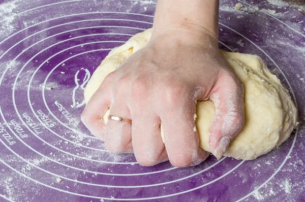 As mãos da mulher amassam a massa em um tapete de silicone . — Fotografia de Stock