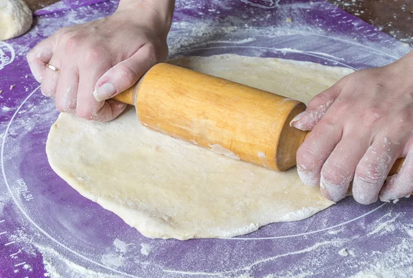 Assar rola a massa em uma esteira de silicone polvilhada com farinha . — Fotografia de Stock